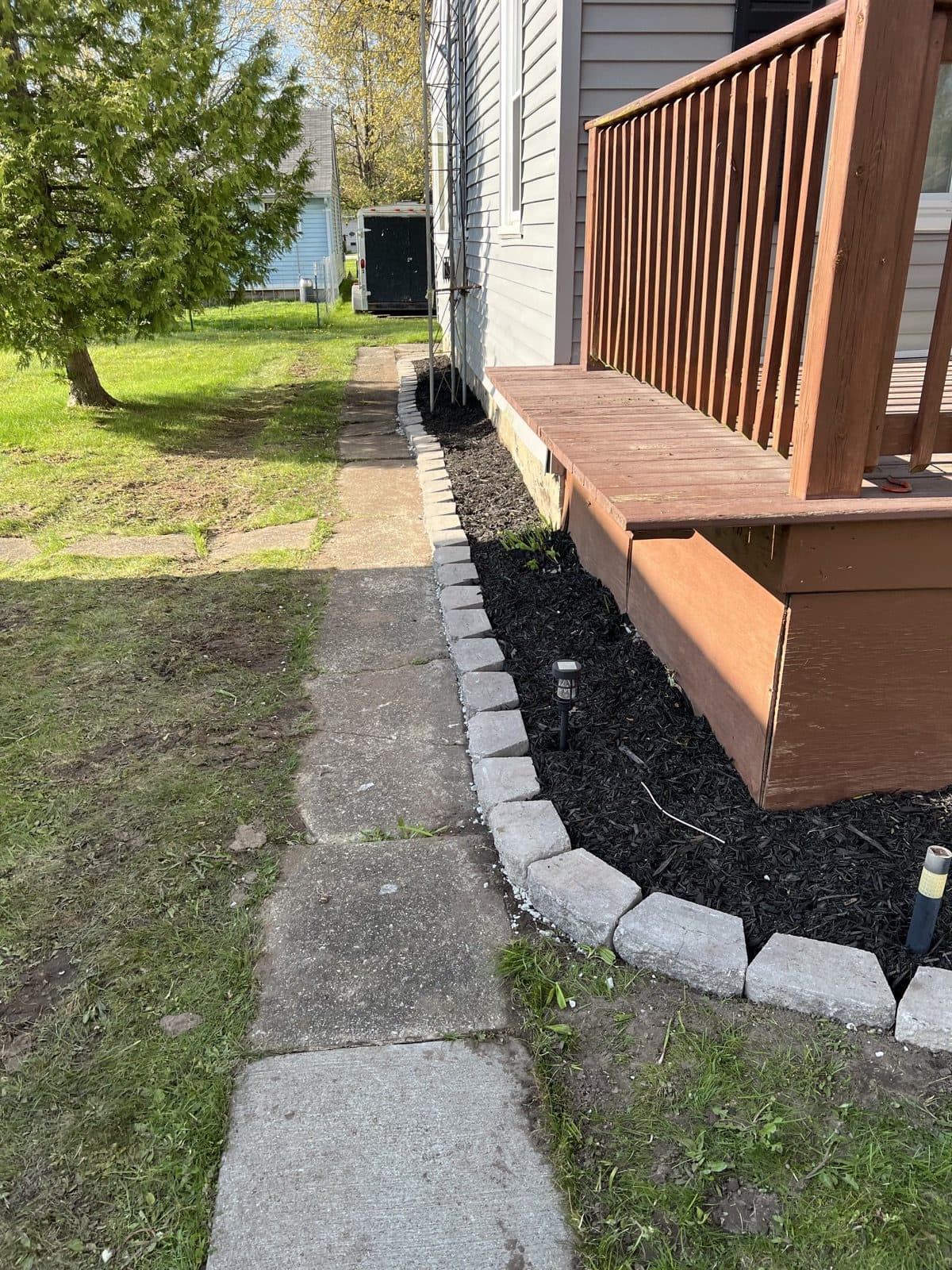 Composite deck with black aluminum railing built onto the side of a sided home
