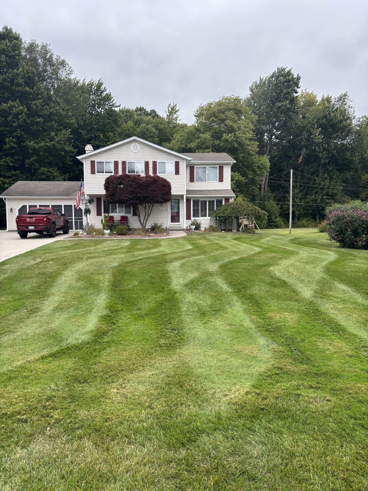 Mowed front lawn with crisp edges and trimmed foundation beds beside a suburban home