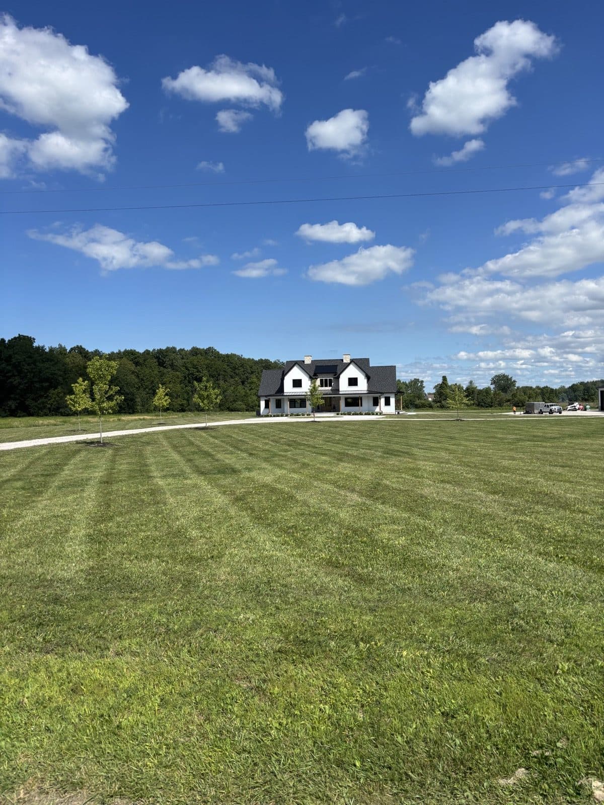 Wide, freshly mowed green lawn under a blue sky beside a Blue Water Area home